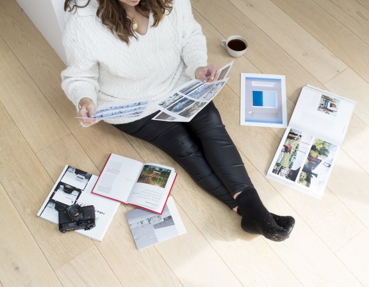 An online photography student sat on the floor with their work