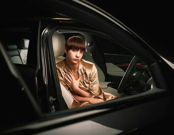 A model wearing gold sitting in a black car