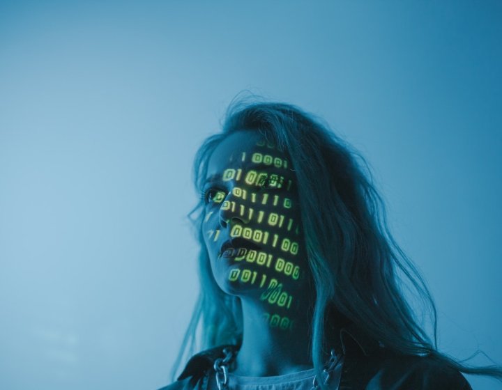 A woman in blue light with yellow numbers projected on her face