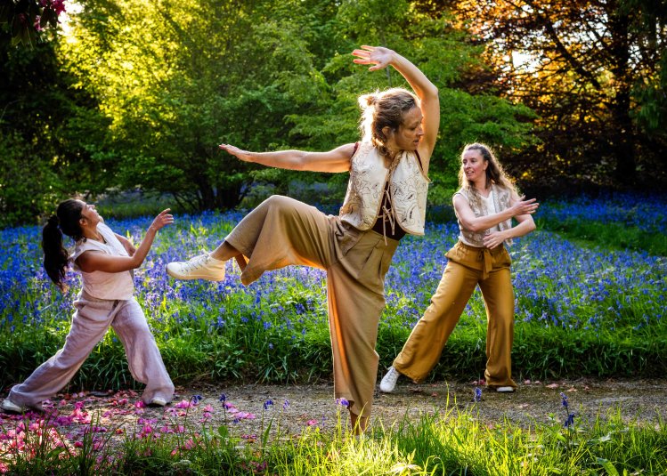 3 dancers performing outside in a woodland setting