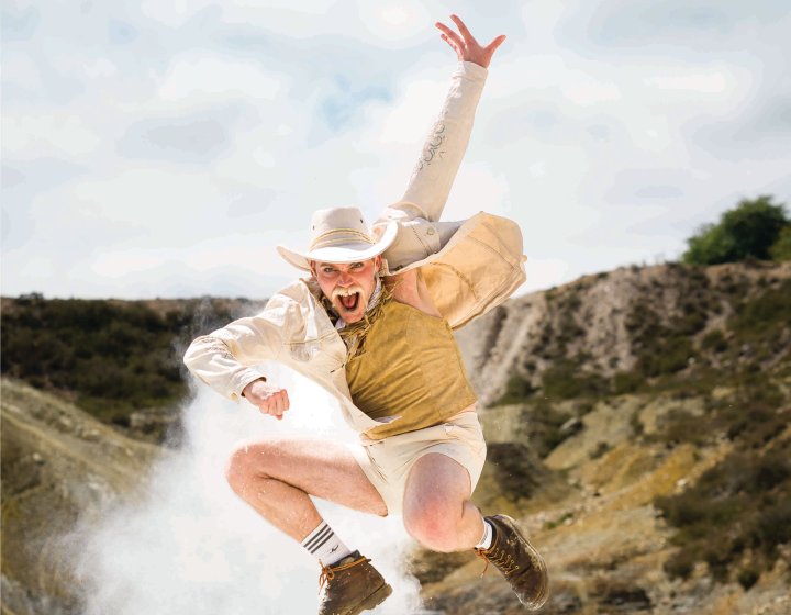 A person dressed as a cowboy jumping in the air in a disused Cornish mine