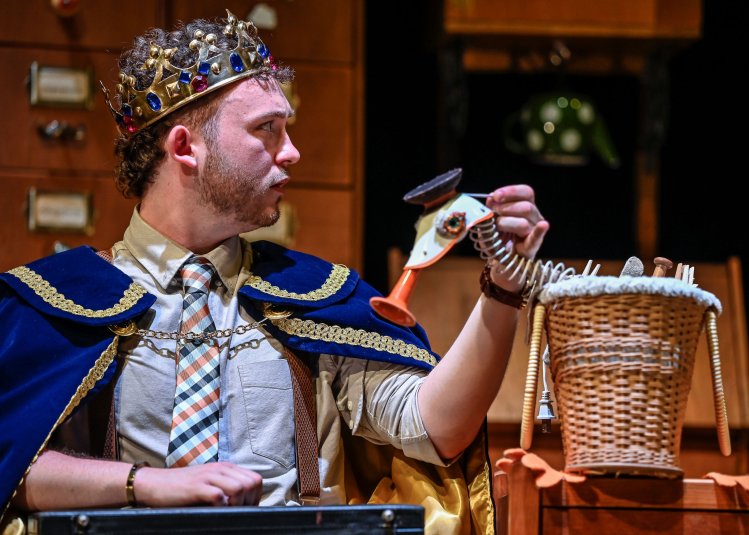 A person on stage performing wearing a crown and using a puppet duck