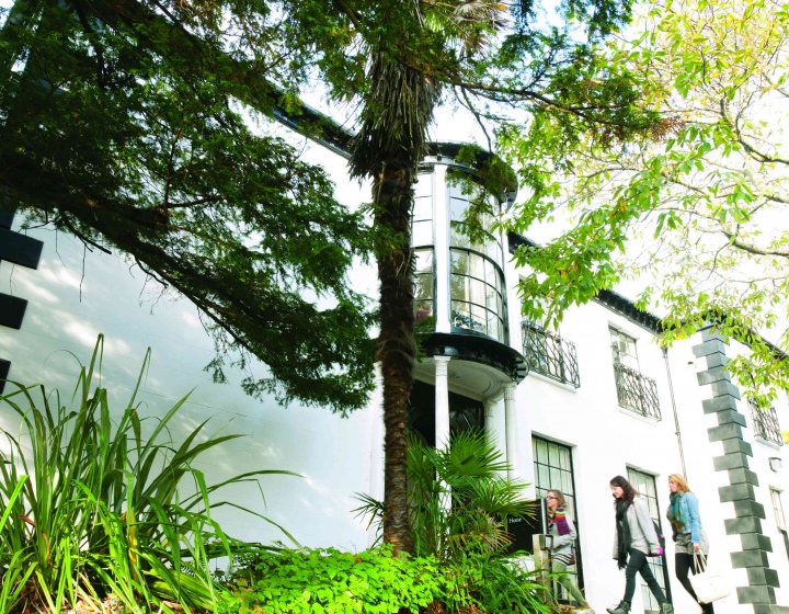 A white building behind greenery