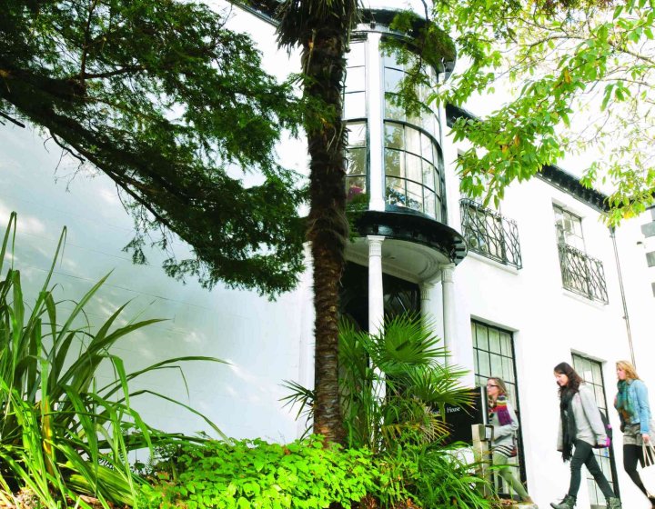 A white building behind greenery