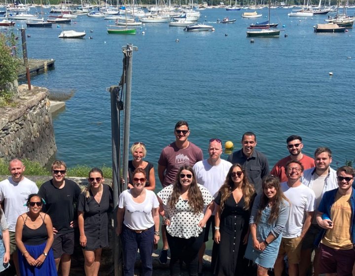 A large group of people standing in front of the sea and boats