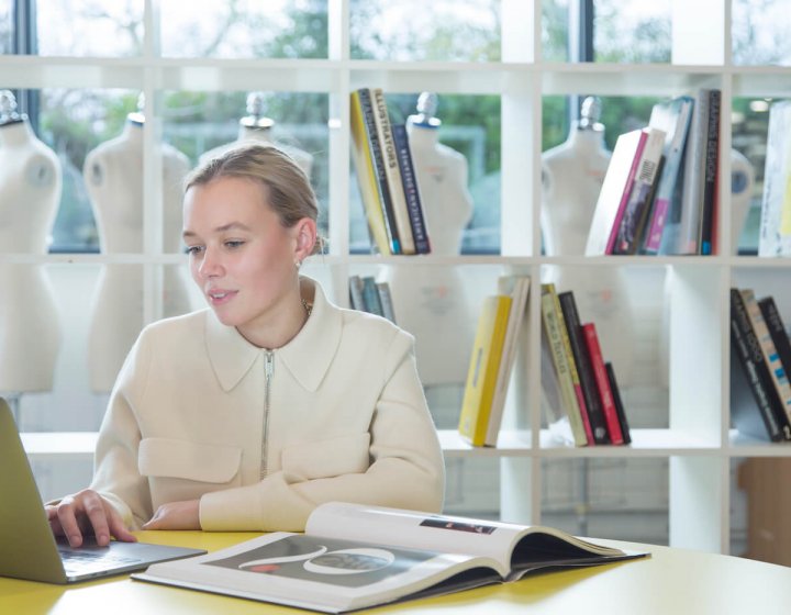 Student working at laptop in front of bookcase