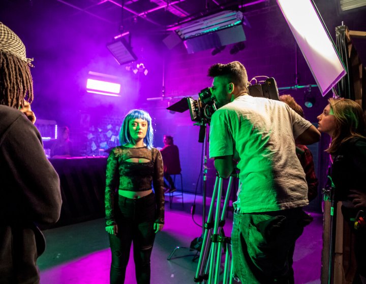 Falmouth University students in a purple lit film studio with camera