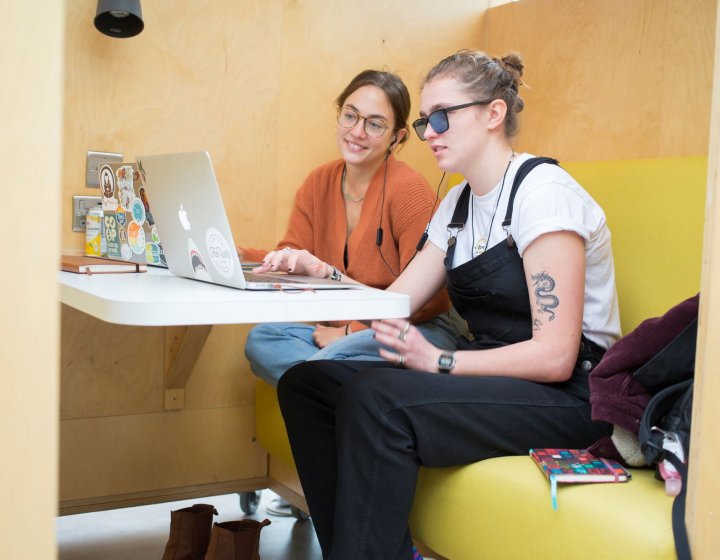 Two students working together around a laptop