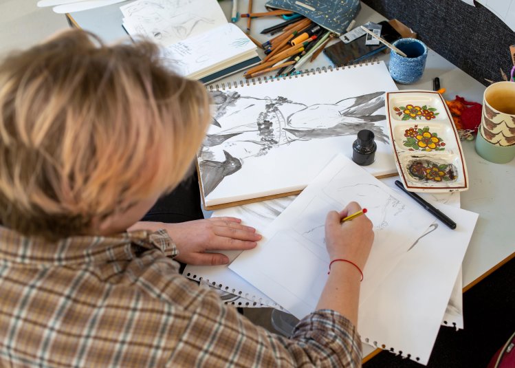 Falmouth Illustration student at cluttered desk drawing a rabbit
