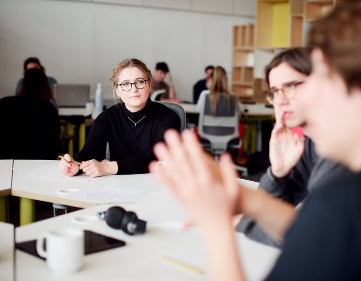 Three people around a white office table