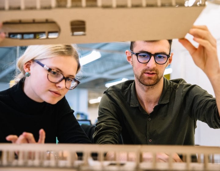 Interior design students looking at cardboard model