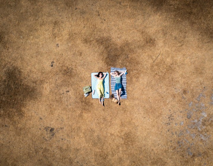 Two sunbathers lying on scorched grass 