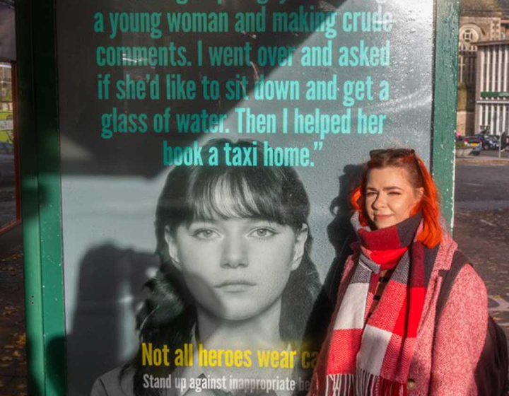 Student Justyna Skowronska standing next to her Safer Cornwall campaign bus stop advert