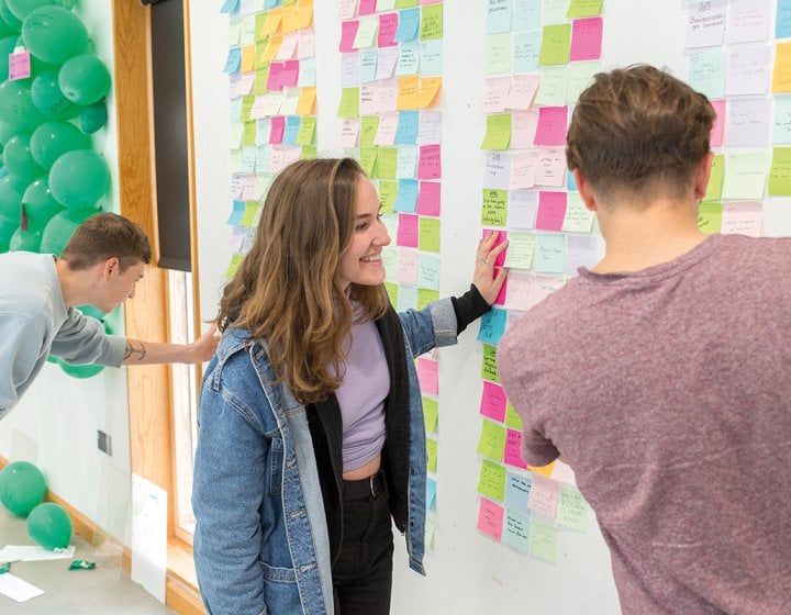 People standing by board with ideas pinned to it