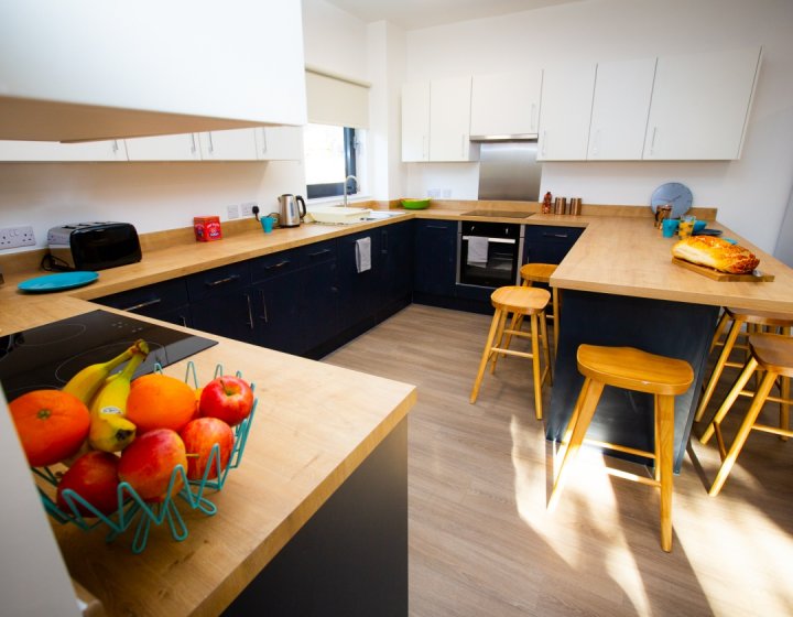 A student kitchen equipped with toaster, kettle, microwave, table, chairs and an oven