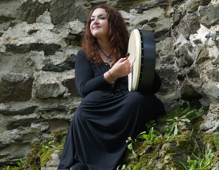 Helen Leahey playing a tambourine on a mountainside