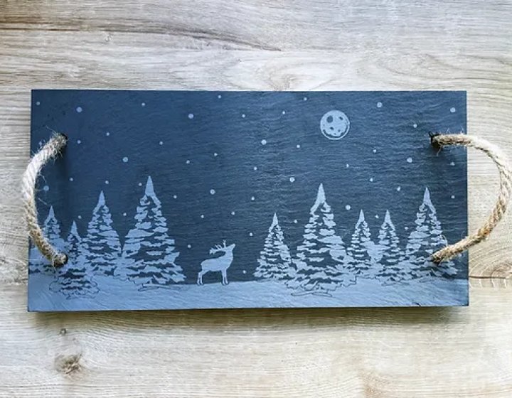 Rectangle piece of slate with etched forest scene with moon to the top right and a deer in the centre. 