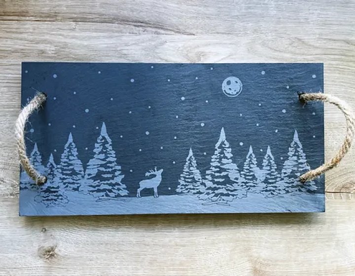 Rectangle piece of slate with etched forest scene with moon to the top right and a deer in the centre.