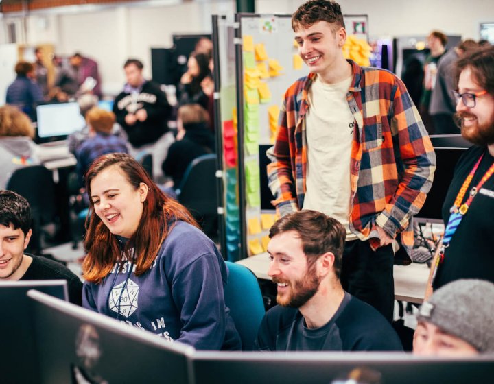 A group of games students smiling and laughing around a computer