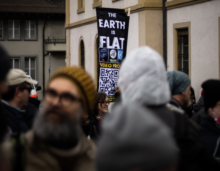A banner raised above a crown with the text 'the earth is flat'
