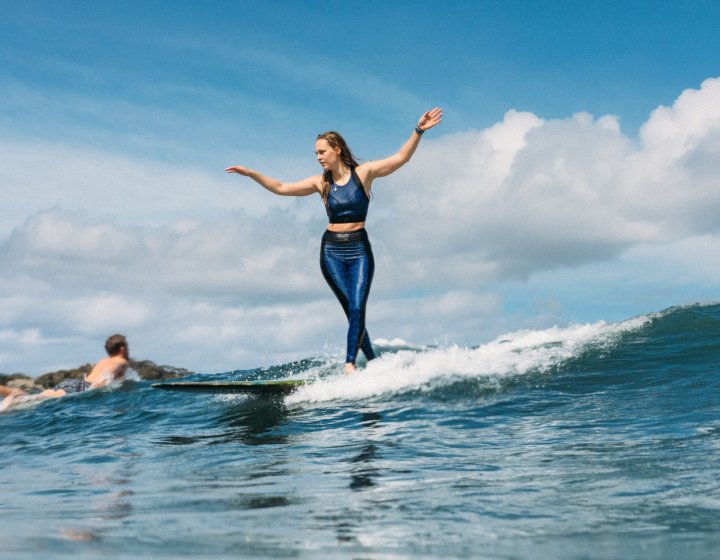 Photo of Falmouth graduate Abbi Hughes surfing on longboard in Cornwall