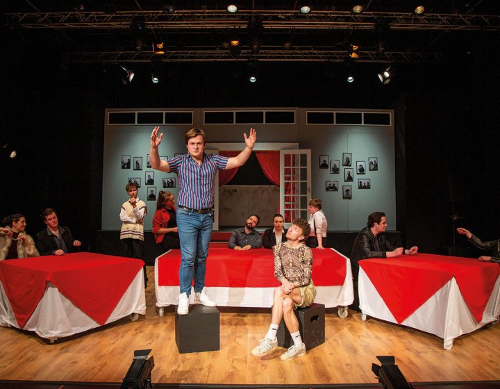 Student stood on a box on stage with arms open