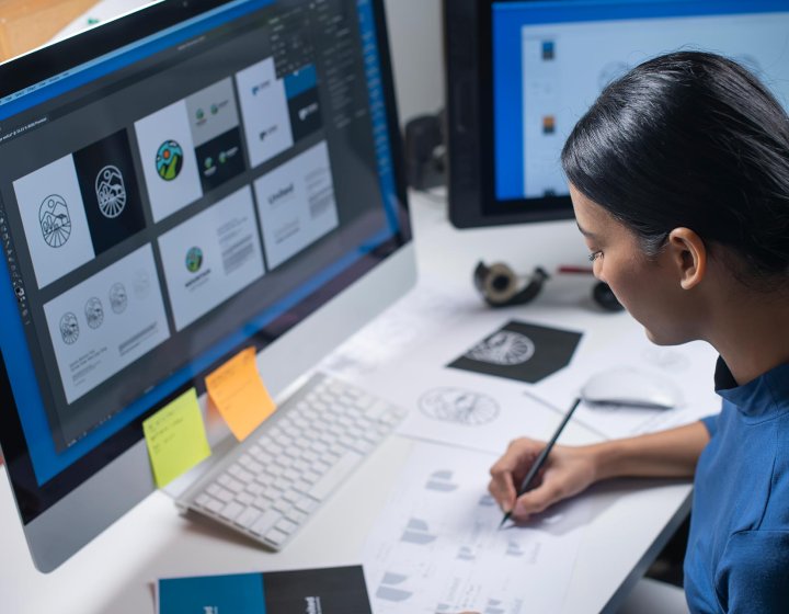 A woman drawing logos at a desktop computer