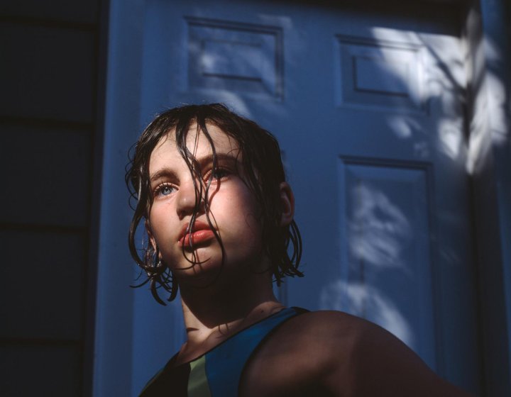 Photograph of a girl with dark wet hair with the sun on her face
