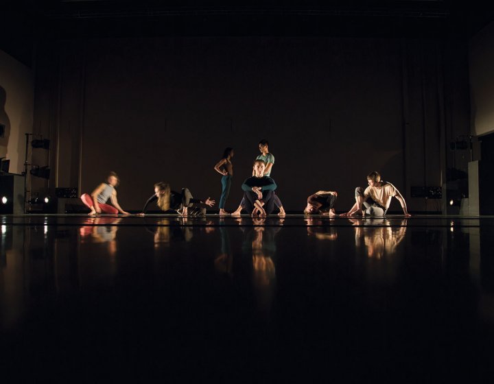Students holding still in dancing positions on a dark stage