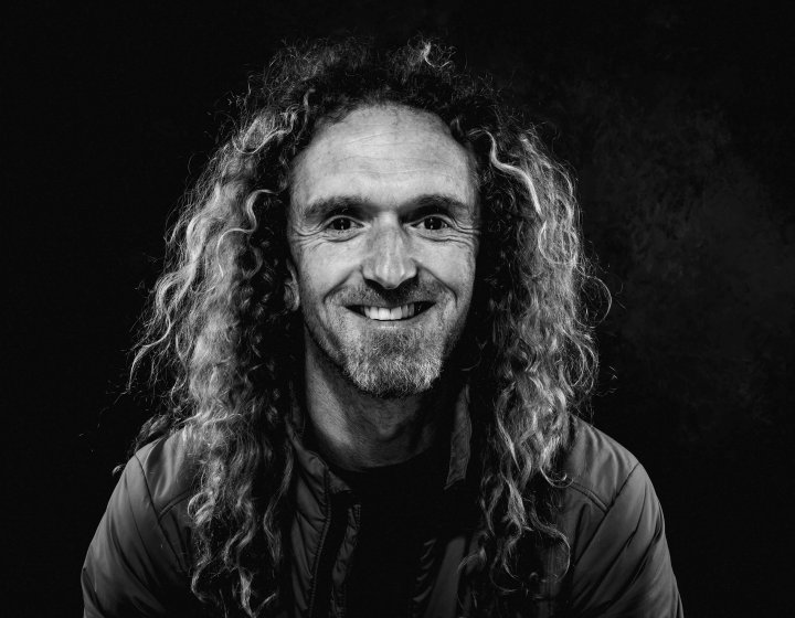 Black and white photo of a man with curly long hair
