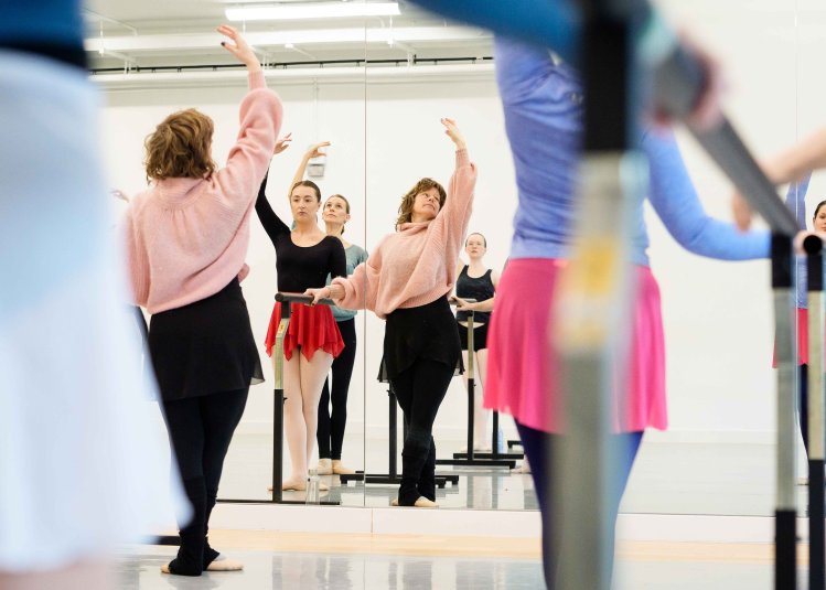 An adult ballet class posing in a studio looking at mirrors
