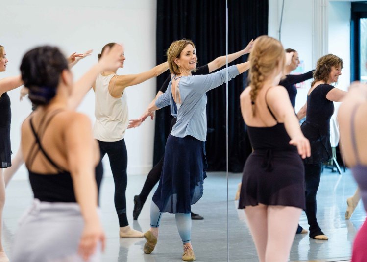 An adult ballet class posing in a studio looking at mirrors
