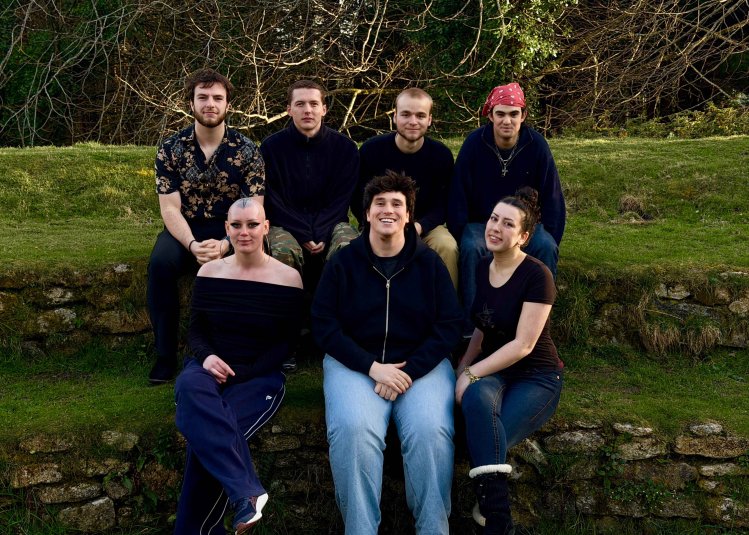 A group of people sat on steps covered in grass