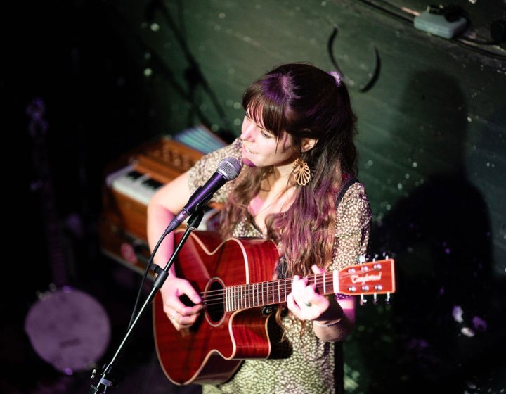 A musical performing with a guitar and singing into a microphone