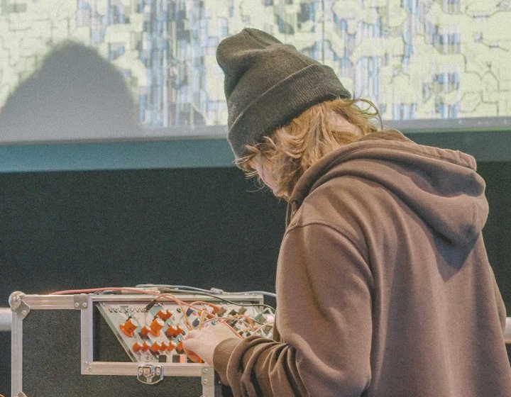 A young person stood at a audio mixing desk