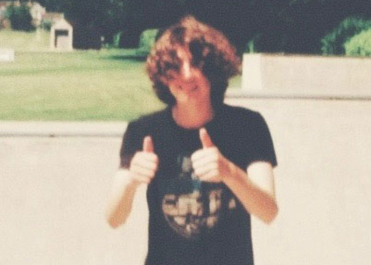 A photo of a person looking at the camera with both of their thumbs up
