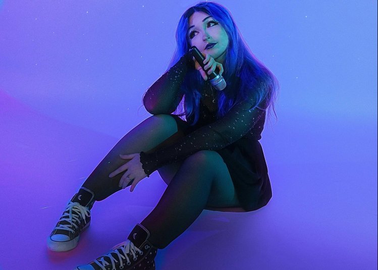 A person sat on the floor with a deep purple light on them