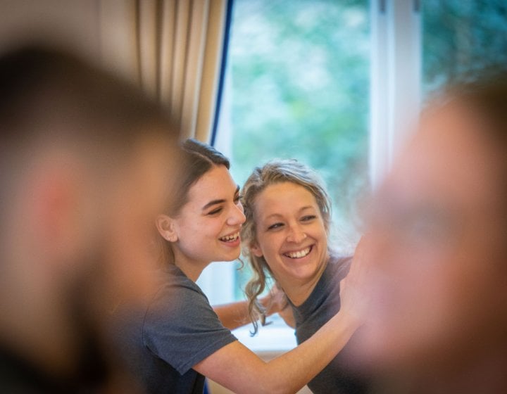 Two people in the background looking towards the camera smiling
