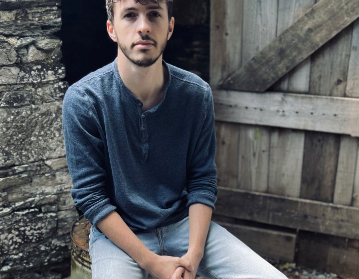 A person sat outside in front of a wooden barn door