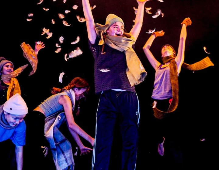 Children dancing and performing on stage throwing feathers into the air