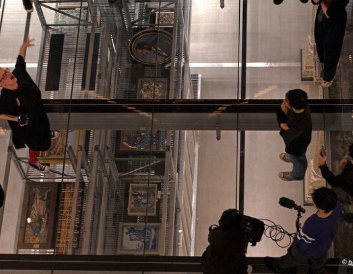 A Birdseye view looking down on performers on a glass floor above a museum gallery