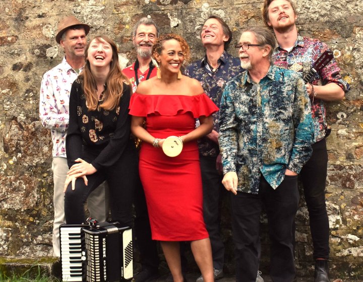 A group of musicians standing against a brick wall holding various musical instrument