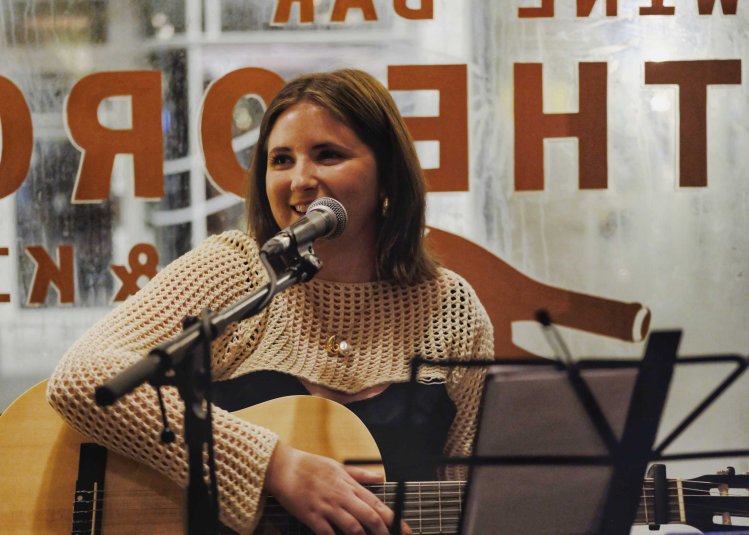 A performer playing the guitar and singing into a microphone