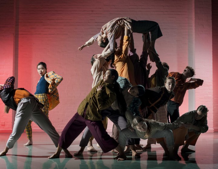 A busy image of lots of dancers moving on space looking towards the camera