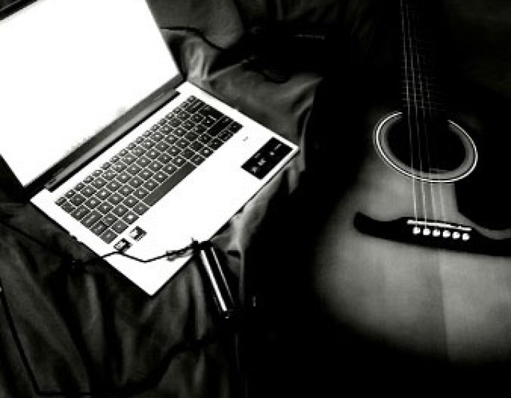 Black and white image of a laptop and guitar