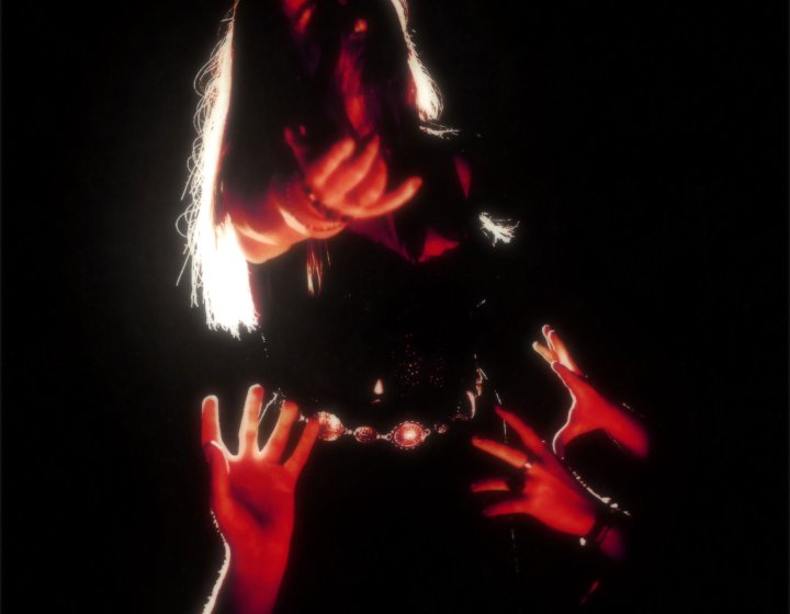 A musican in darkness with a small amount of red light on them