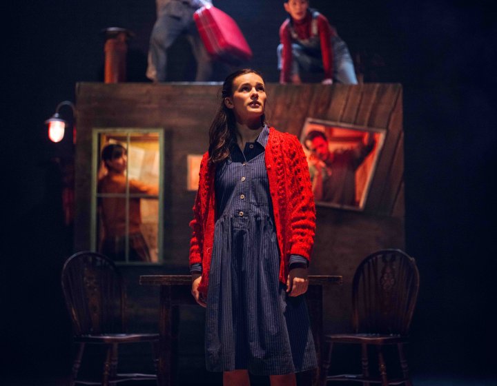 Theatrical performers on stage against a dramatic stage set in the background