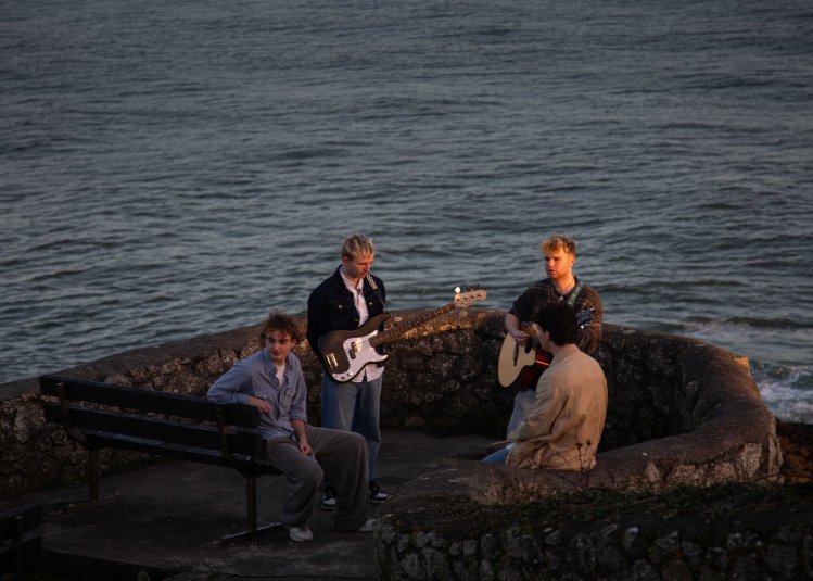 A group of musicians outside with a sea in the background