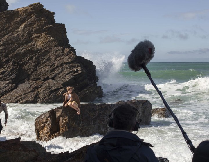 Woman on rock in sea being filmed