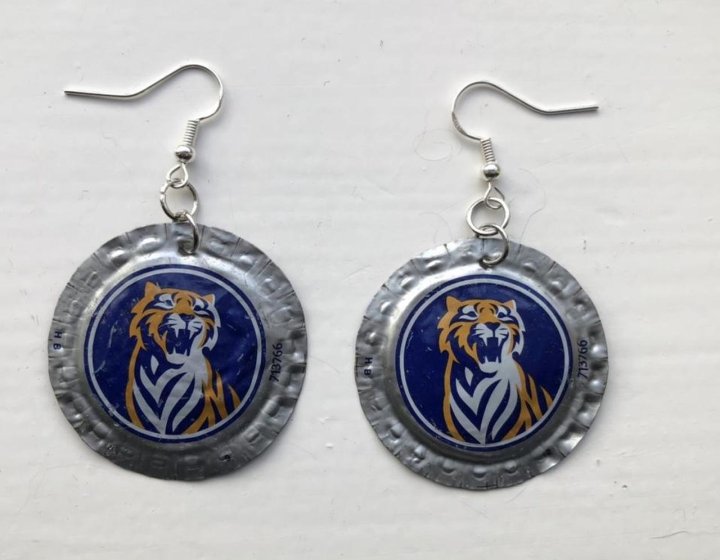 Pair of circular metal earrings, featuring tiger on blue background, made out of beer bottle tops.